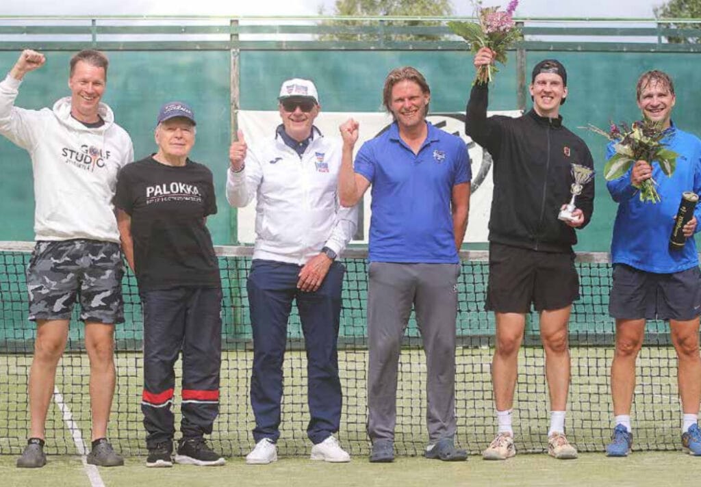 Kilpailupäällikkö Jarkko Soikkeli, turnauksen suojelija Jorma Hänninen, ylituomari Pentti Keiskoski, turnausvastaava Perttu Hautala, kaksinpelin mestari Henri Lahti ja kaksinpelin finalisti Tuomas Alasaarela seisovat tenniskentällä verkon edessä.