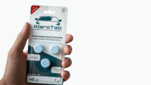 Käsi ojentaa KlaroTab lasinpesunestetabletti-pakettia.