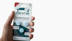 Käsi ojentaa KlaroTab lasinpesunestetabletti-pakettia.