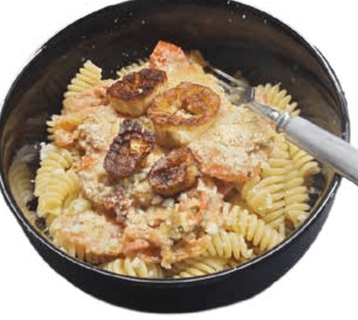 Herkkutattipastaa mustassa kulhossa. Paistettuja tatin jalkoja pastan päällä parmesan-juuston kera.